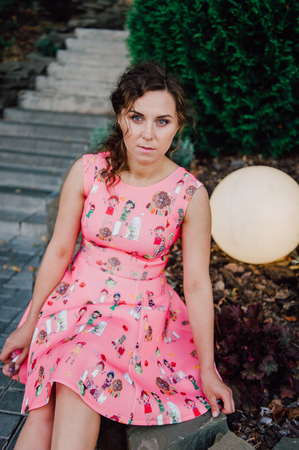 Beautiful brunette girl posing in pink dress outside near tropical plantsの写真素材