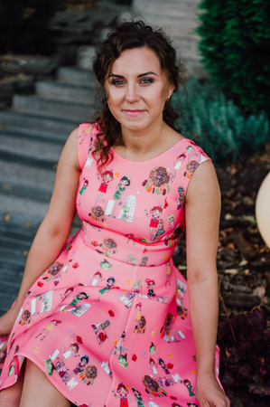 Beautiful brunette girl posing in pink dress outside near tropical plantsの写真素材