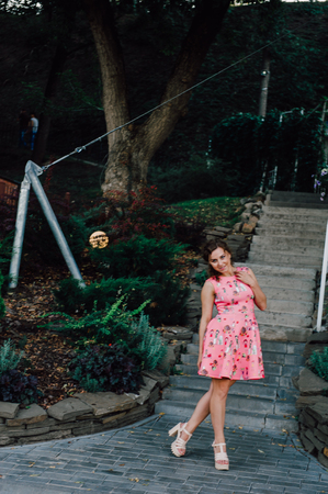 Beautiful brunette girl posing in pink dress outside near tropical plantsの写真素材