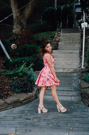 Beautiful brunette girl posing in pink dress outside near tropical plantsの写真素材