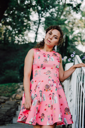 Beautiful brunette girl posing in pink dress outside near tropical plantsの写真素材