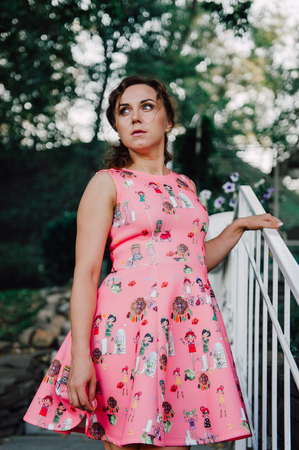 Beautiful brunette girl posing in pink dress outside near tropical plantsの写真素材