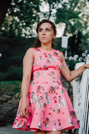 Beautiful brunette girl posing in pink dress outside near tropical plantsの写真素材