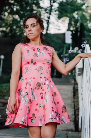 Beautiful brunette girl posing in pink dress outside near tropical plantsの写真素材