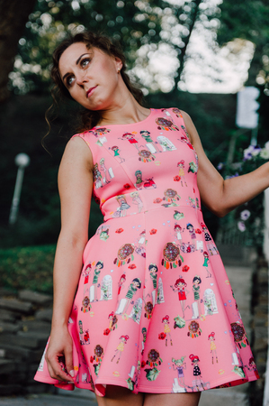 Beautiful brunette girl posing in pink dress outside near tropical plantsの写真素材