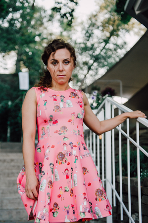 Beautiful brunette girl posing in pink dress outside near tropical plantsの写真素材