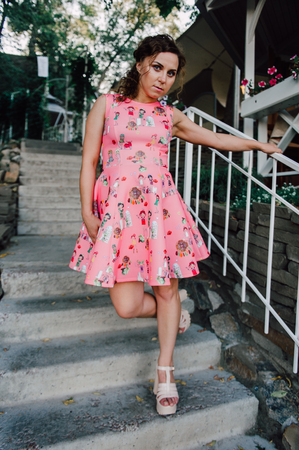 Beautiful brunette girl posing in pink dress outside near tropical plantsの写真素材