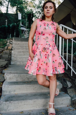 Beautiful brunette girl posing in pink dress outside near tropical plantsの写真素材