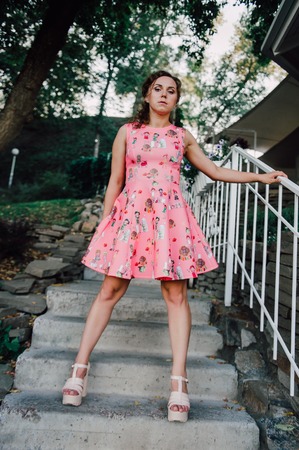 Beautiful brunette girl posing in pink dress outside near tropical plantsの写真素材