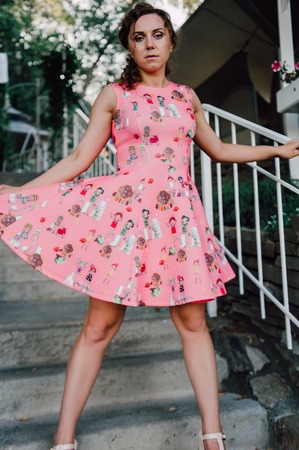 Beautiful brunette girl posing in pink dress outside near tropical plantsの写真素材