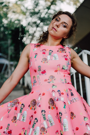 Beautiful brunette girl posing in pink dress outside near tropical plantsの写真素材
