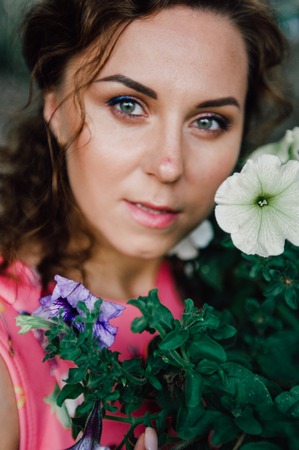 Beautiful brunette girl posing in pink dress outside near tropical plantsの写真素材