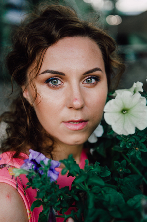 Beautiful brunette girl posing in pink dress outside near tropical plantsの写真素材