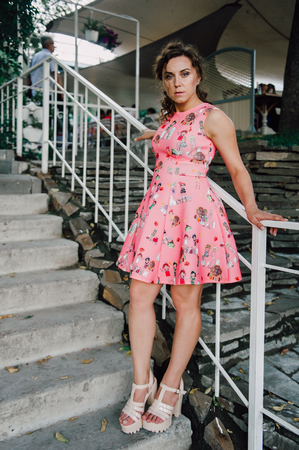 Beautiful brunette girl posing in pink dress outside near tropical plantsの写真素材