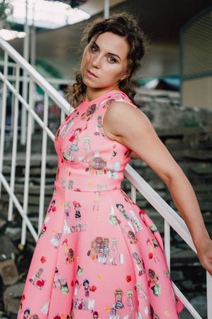 Beautiful brunette girl posing in pink dress outside near tropical plantsの写真素材