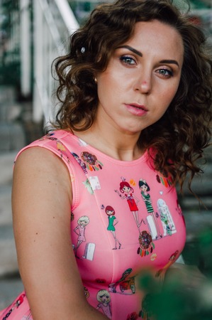 Beautiful brunette girl posing in pink dress outside near tropical plantsの写真素材
