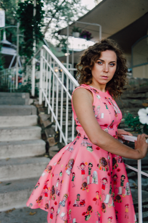 Beautiful brunette girl posing in pink dress outside near tropical plantsの写真素材