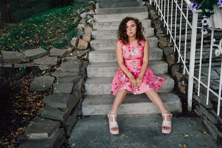 Beautiful brunette girl posing in pink dress outside near tropical plantsの写真素材
