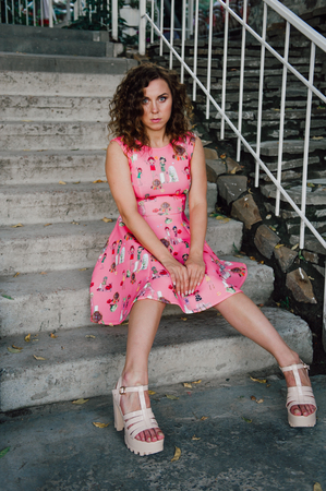 Beautiful brunette girl posing in pink dress outside near tropical plantsの写真素材