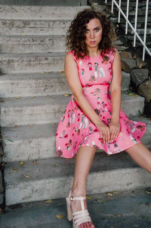 Beautiful brunette girl posing in pink dress outside near tropical plantsの写真素材