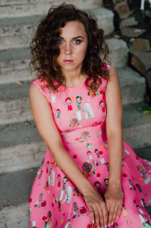 Beautiful brunette girl posing in pink dress outside near tropical plantsの写真素材