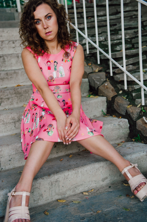 Beautiful brunette girl posing in pink dress outside near tropical plantsの写真素材