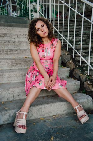 Beautiful brunette girl posing in pink dress outside near tropical plantsの写真素材