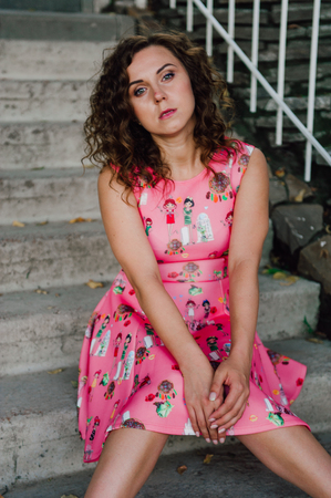Beautiful brunette girl posing in pink dress outside near tropical plantsの写真素材