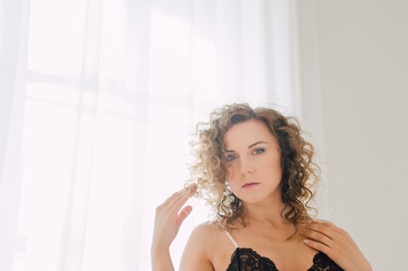 Sexy woman in bed in the morning showing her beautiful body. She doesn't wants to wake up. Awaken with natural light in her bedroom and covered with the bed sheets.の写真素材