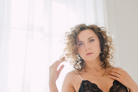 Sexy woman in bed in the morning showing her beautiful body. She doesn't wants to wake up. Awaken with natural light in her bedroom and covered with the bed sheets.の写真素材