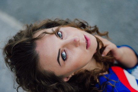 Beautiful sexy young brunette girl with long wavy hair thin slender figure and pretty face make-up wearing a long stripped skirt and black top, high heels. Walk on the street in casual styleの写真素材