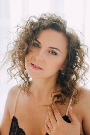 Sexy woman in bed in the morning showing her beautiful body. She doesn't wants to wake up. Awaken with natural light in her bedroom and covered with the bed sheets.の写真素材