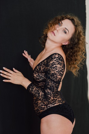 Sexy and beautiful woman wearing black lace body lingerie with curly hairの写真素材