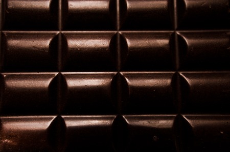 Cup of coffee with grains and chocolate on wooden table on dark backgroundの写真素材