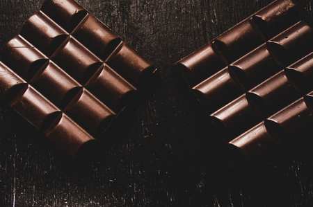 Cup of coffee with grains and chocolate on wooden table on dark backgroundの写真素材