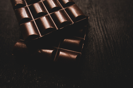Cup of coffee with grains and chocolate on wooden table on dark backgroundの写真素材