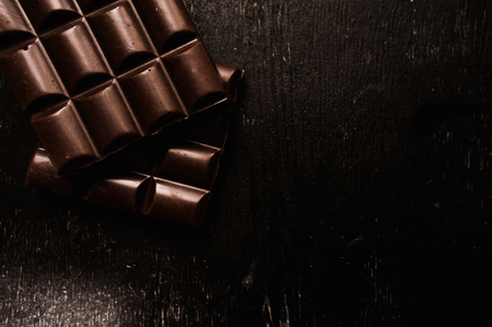 Cup of coffee with grains and chocolate on wooden table on dark backgroundの写真素材
