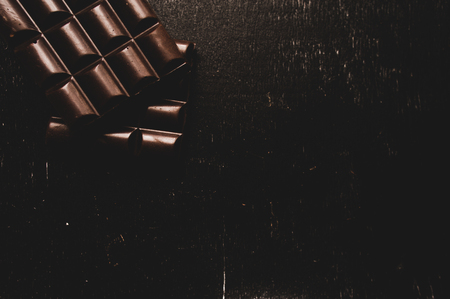 Cup of coffee with grains and chocolate on wooden table on dark backgroundの写真素材