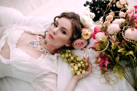 Beautiful young woman, hair decorated with flowers. Perfect makeup. Beauty fashion. Eyelashes. Studio retouched shot. Tender and sweet atmosphere, pastel colorsの写真素材