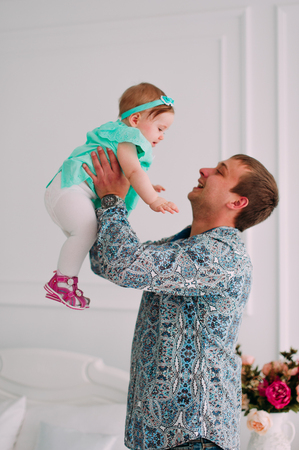 Portrait of a grandfather wearing blue  shirt with his small pretty granddaughter hugging him and listening attentively, studio shotの写真素材