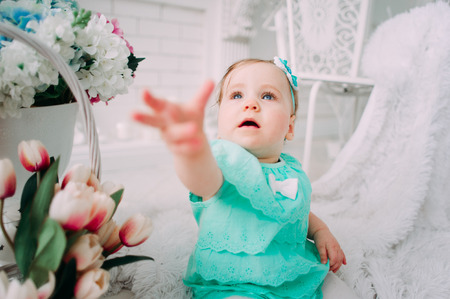Adorable little baby girl laughing, smiling, creeping & playing in the studio wearing mint dressの写真素材