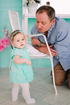 Portrait of a grandfather wearing blue  shirt with his small pretty granddaughter hugging him and listening attentively, studio shotの写真素材