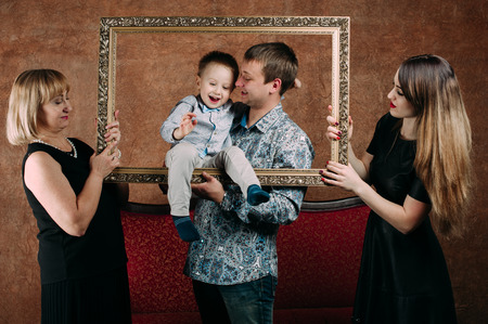 Three Generation Family Sitting On Sofa Together. Classic portrait in a frameの写真素材