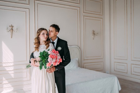 cute wedding couple in the interior of a classic studio decorated. hey kiss and hug each otherの写真素材