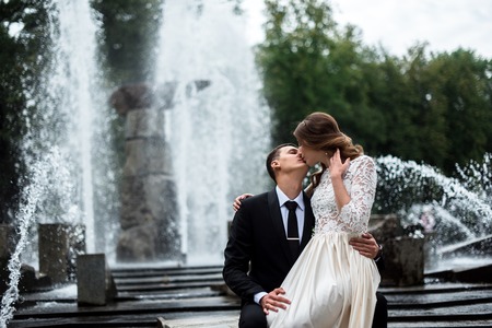 Bride and groom kissing with the fountain on the backgroundの写真素材