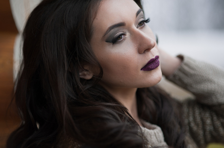 Spring in the country style. Full length portrait of young woman in white knitted sweater and furry hat standing in the front of rustic wood wall in the yard near house, wearing sweaterの写真素材