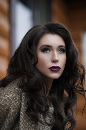 Spring in the country style. Full length portrait of young woman in white knitted sweater and furry hat standing in the front of rustic wood wall in the yard near house, wearing sweaterの写真素材