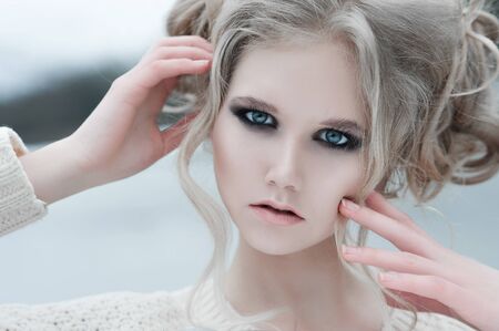 Close up of beautiful young  blonde woman with blue eyes in white pullover. 
Winter, spring, outdoor...