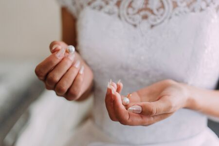 A bride is holding the beautiful jewelry (earrings, pendant) in the handの写真素材