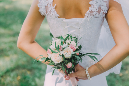 Beautiful wedding bouquet in hands of the bride. Peony rose, cotton, roses. Pink and Peach. Trendy and modern wedding flowers. Ideal photo for commercial.の写真素材